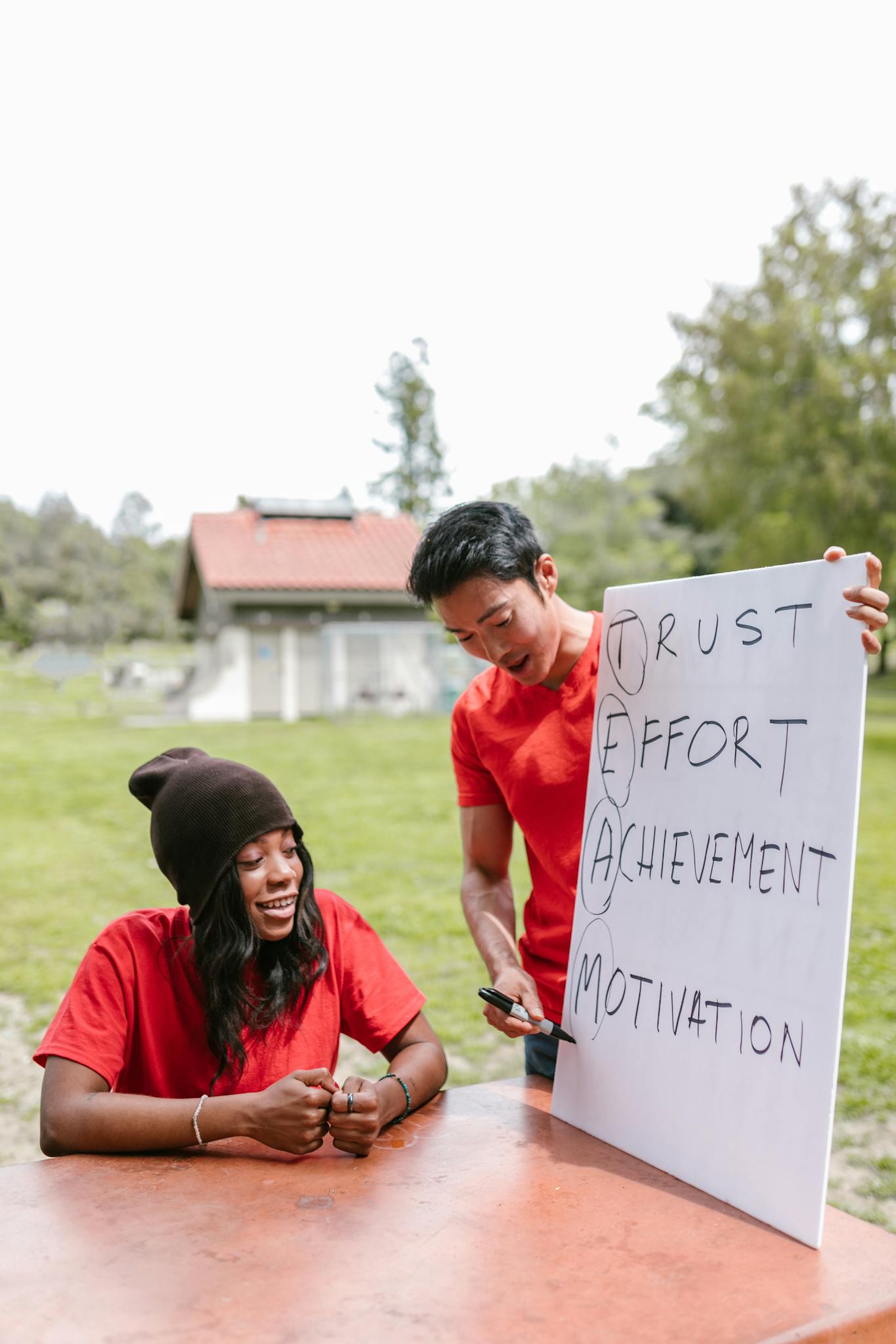 Two adults engaging in an outdoor team building activity with a motivational sign, showing teamwork and collaboration.